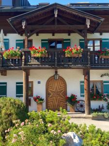 una casa con macetas de flores en el balcón y una puerta de madera en Oberstöberl, en Bischofswiesen