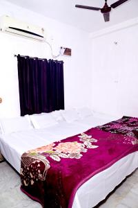 ein Schlafzimmer mit einem Bett mit einer lila Decke darauf in der Unterkunft SHIVAY Guest House in Deoghar