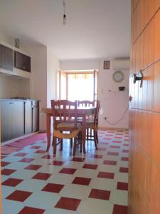 een keuken met een tafel en stoelen op een geruite vloer bij La dolce vita, relax & kite Falerna in Falerna