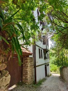 a white house with a stone wall and trees at Asya konak in Safranbolu