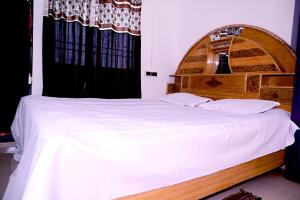 Schlafzimmer mit einem großen weißen Bett mit einem Kopfteil aus Holz in der Unterkunft SHIVAY Guest House in Deoghar