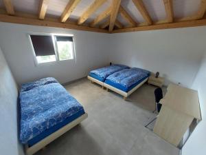 1 Schlafzimmer mit 2 Betten, einem Tisch und einem Fenster in der Unterkunft Chambres de la Tuilerie in Saignelégier