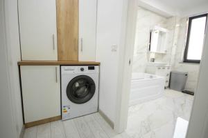 a white bathroom with a washing machine in it at DownTown Apartments in Rădăuţi