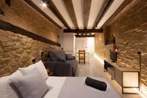 a bedroom with a stone wall with a bed and a couch at Palacio del Marqués en Logroño con parking próximo in Logroño