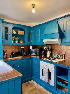 a blue kitchen with blue cabinets and a stove at Park View in Quorndon