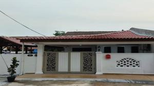una pequeña casa blanca con techo rojo en AliyaRoseMuslim Homestay en Ayer Keroh