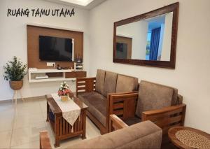 a living room with a couch and a tv at AliyaRoseMuslim Homestay in Ayer Keroh