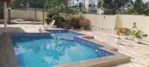 a swimming pool with blue tiles in a backyard at Quarto inteiro com banheiro privativo in Salvador