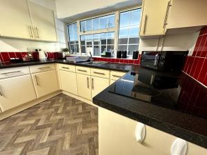 a kitchen with white cabinets and black counter tops at Kennedy Villa - 5 Bedroom House with Hot Tub, WiFi, Free parkings, Close to Bicester Village in Bicester