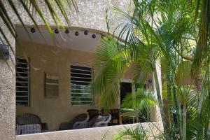 een patio met stoelen en palmbomen voor een gebouw bij Caribbean Happyness in Willemstad