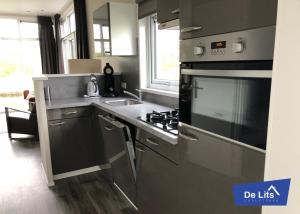 a kitchen with a stainless steel stove and a sink at Chaletpark de Lits in Oostermeer