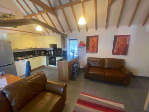a living room with two leather couches and a kitchen at Seafret Barn sleeps two, North Norfolk in Roughton