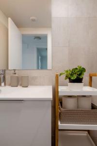 a bathroom with a sink and a mirror and a plant at Precioso apartamento en residencial con piscina in Valencia