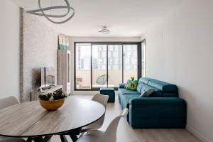 a living room with a blue couch and a table at Precioso apartamento en residencial con piscina in Valencia