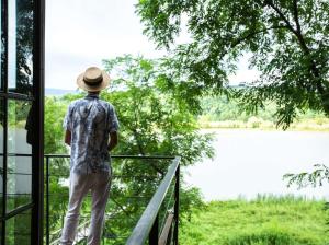 a man standing on a balcony looking out at a lake at Porto Gumati in Kutaisi