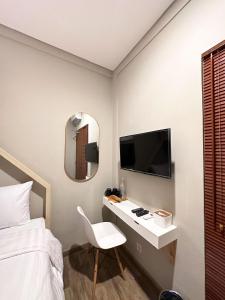 a bedroom with a bed and a desk with a tv at Lugano Arte Homestay in Jakarta