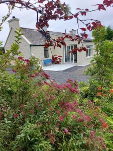 a white house with a bunch of flowers in front of it at Harmony Haven Cottage in Foxford