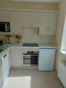 a kitchen with white cabinets and a stove top oven at Harmony Haven Cottage in Foxford