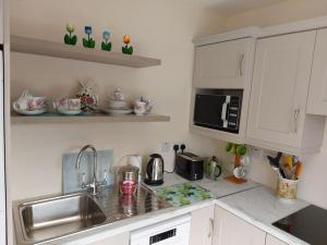 cocina con fregadero y microondas en Harmony Haven Cottage en Foxford