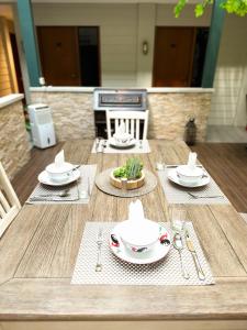 a wooden table with plates and utensils on it at Lugano Arte Homestay in Jakarta