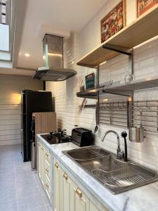 a kitchen with a sink and a black refrigerator at Lugano Arte Homestay in Jakarta