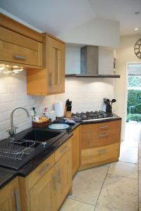a kitchen with wooden cabinets and a black counter top at IVY COTTAGE in Pulborough