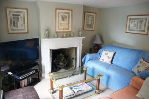 - un salon avec un canapé bleu et une cheminée dans l'établissement IVY COTTAGE, à Pulborough