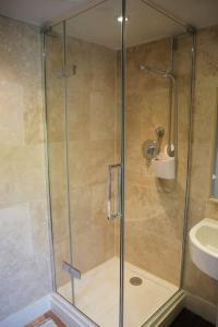 une douche avec une porte en verre à côté d'un lavabo dans l'établissement IVY COTTAGE, à Pulborough