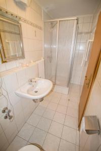 a white bathroom with a sink and a shower at Gasthof zur Länd in Moosburg