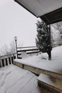 a porch covered in snow next to a fence at Il giardino sulle Piste in Prato Nevoso