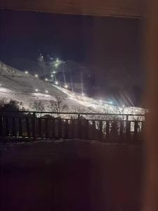una colina cubierta de nieve con una valla y luces en Il giardino sulle Piste en Prato Nevoso