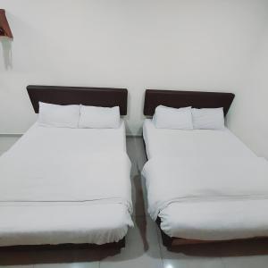 two beds with white sheets sitting next to each other at Hotel Lean Fatt in Ipoh