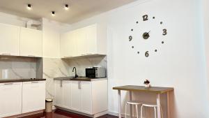 uma cozinha com armários brancos e um relógio na parede em Arlan apartments em Almaty