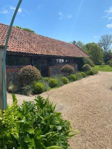 a brick house with a roof and some bushes at Oyster Barn sleeps six, North Norfolk in Roughton