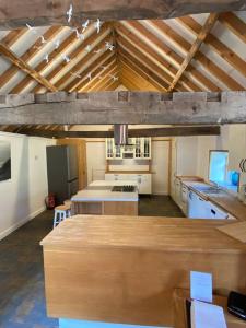 a large room with a kitchen with wooden ceilings at Oyster Barn sleeps six, North Norfolk in Roughton
