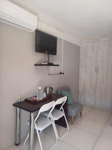 Habitación con mesa y TV en la pared. en @Home BnB en Maseru