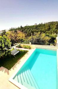 a blue swimming pool with a chair in a yard at Paradise House Ground floor apartment in Villa with private pool and private garden in Abrantes