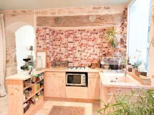 a kitchen with a brick wall and a sink at Appartement au rez-de-chaussée in Souillac