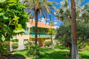 ein gelbes Haus mit Palmen davor in der Unterkunft Hacienda San Jorge in Breña Baja