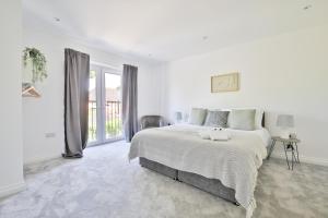 a white bedroom with a large bed and a window at StayRight Spacious Apartments with Private Parking- 15-Minute Stroll to Town Centre in Cardiff