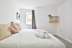 a white bed with two stuffed animals on it at StayRight Spacious Apartments with Private Parking- 15-Minute Stroll to Town Centre in Cardiff