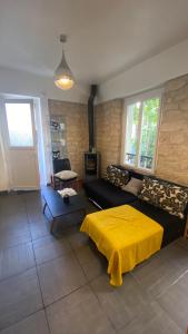 ein Wohnzimmer mit einem schwarzen Sofa und einer gelben Decke in der Unterkunft Charmante maison en ville Paris in Charenton-le-Pont