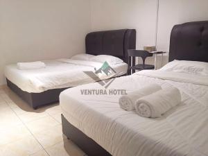 Habitación de hotel con 2 camas y toallas. en Ventura Hotel and Tours, en Gua Musang