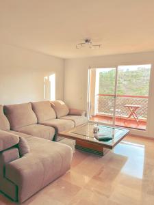 Albatross Golf Suite Alcaidesa في ألكيديسا: غرفة معيشة مع أريكة وطاولة قهوة زجاجية