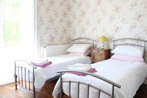 two twin beds in a room with floral wallpaper at La Belle Maison in Eymoutiers +16 photos