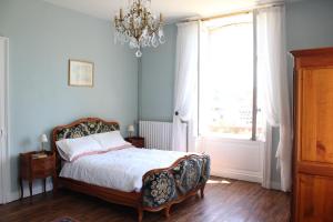 a bedroom with a bed and a chandelier at La Belle Maison in Eymoutiers