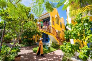 uma mulher a andar em frente a uma casa amarela em Chez Mimosa Hoi An - LUA Retreat em Hoi An
