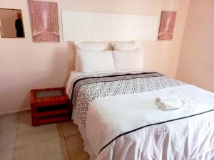 una camera da letto con un letto con copriletto bianco di Lindo Guest house a Estcourt