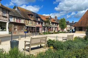 a park with two benches in a town with buildings at maison normande en paix 