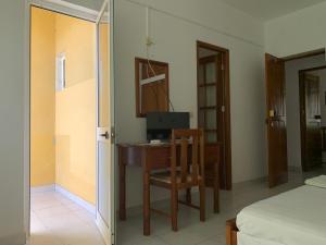 a bedroom with a desk with a computer and a chair at Residencial Pôr do Sol in Porto Novo